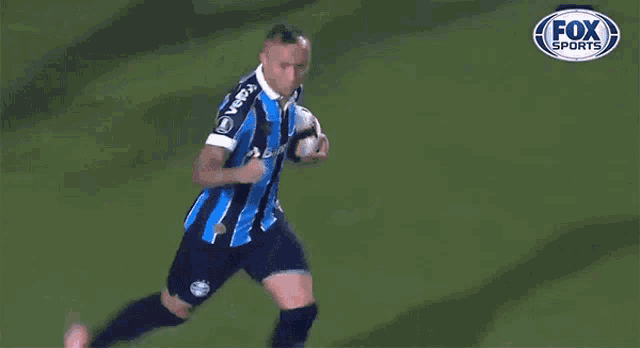 a soccer player is running on the field with the fox sports logo in the background
