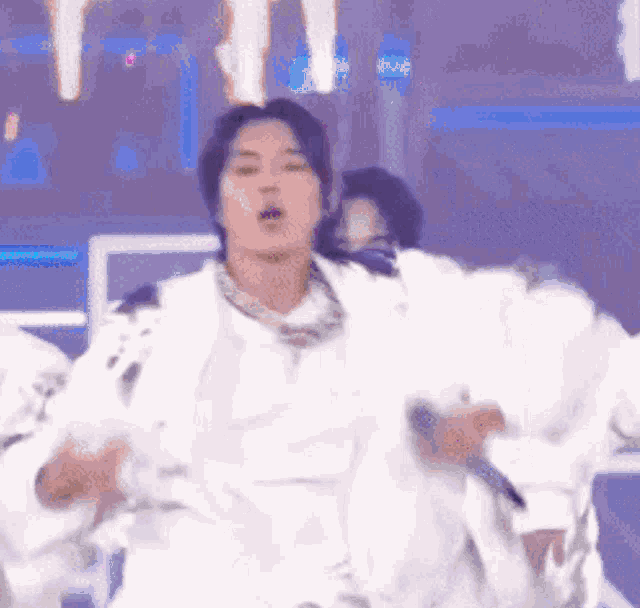 a man in a white jacket is dancing on a stage in front of a crowd .