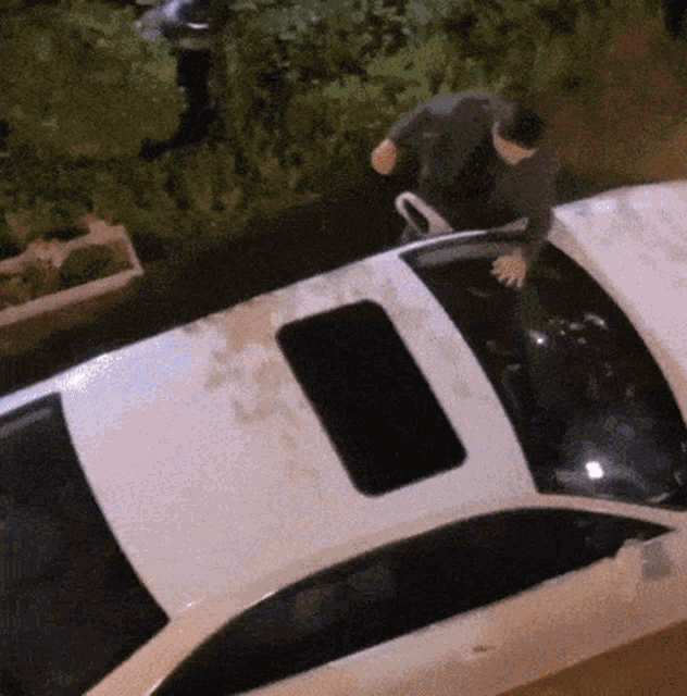 a man standing on top of a white car