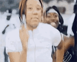 a woman in a white shirt is giving the middle finger while standing next to another woman .