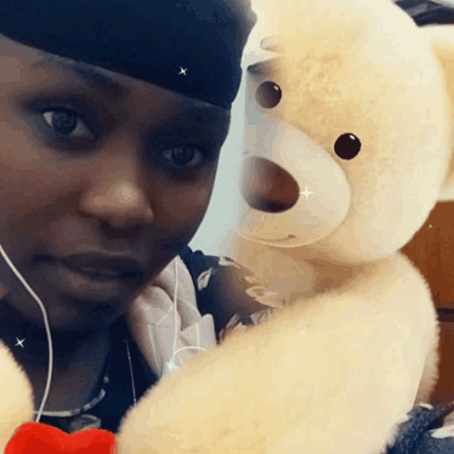 a woman holding a teddy bear with a red bow around her neck