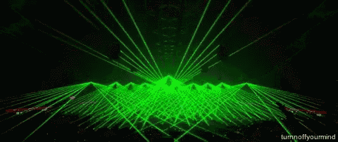 a crowd of people watching a concert with green lights coming out of the ceiling