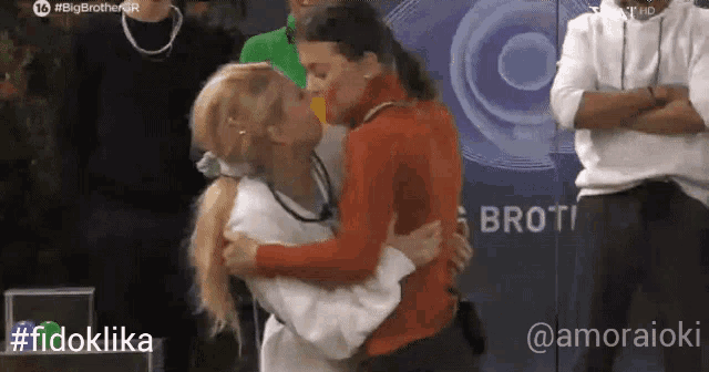 two women are hugging each other in front of a sign that says broti
