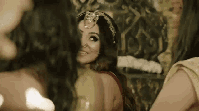 a woman with a nose ring is smiling in front of a group of women