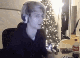 a man wearing headphones sitting in front of a christmas tree