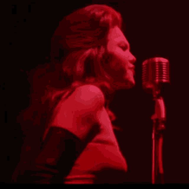 a woman singing into a microphone in a dark room