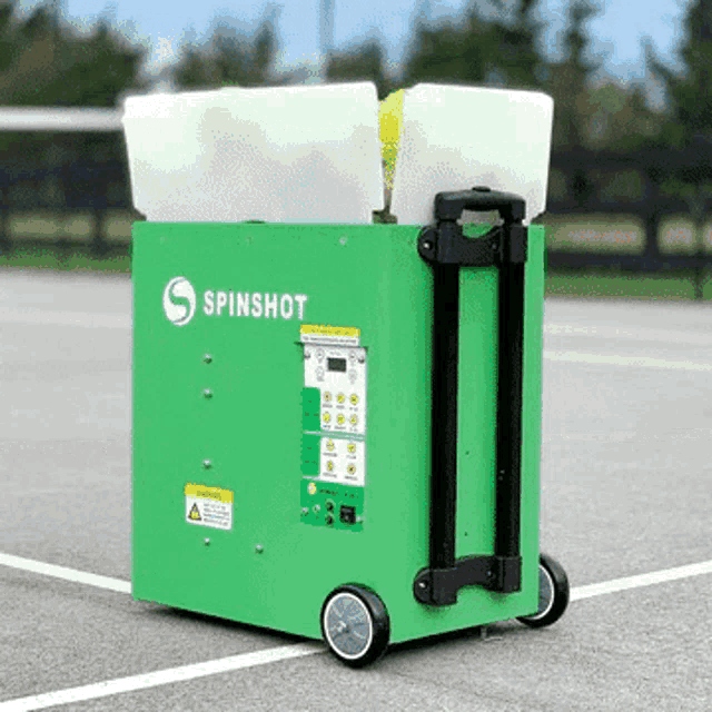 a green spinshot machine is on wheels on a tennis court