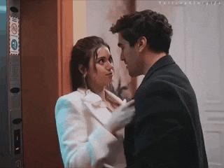 a man and a woman are standing next to each other in front of a door and kissing .