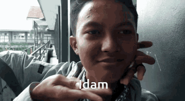 a young man is making a funny face and the word idam is on the bottom