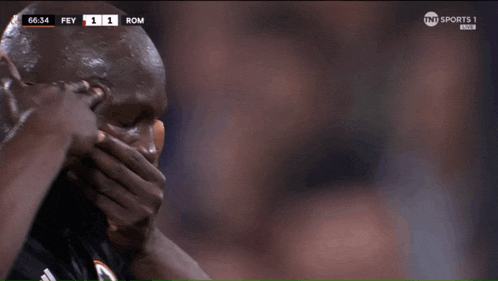 a man covering his face with his hands while watching a tnt sports 1 broadcast
