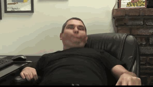 a man in a black shirt is sitting in a chair making a funny face