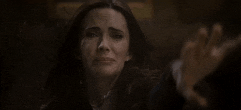a woman is crying while holding a man 's hand in front of her face .