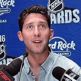 a man is speaking into a microphone in front of a nhl awards banner