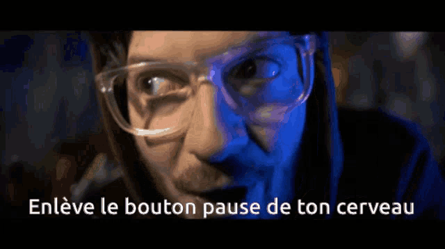 a close up of a man wearing glasses with the words enleve le bouton pause de ton cerveau above him