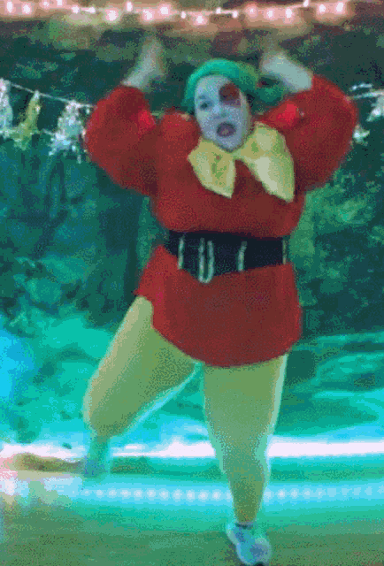 a woman in a clown costume is dancing in front of a blue background
