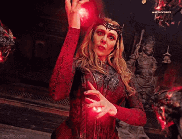 scarlet witch is holding a red glowing object in her hand .