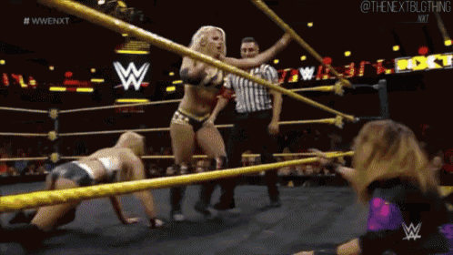 a woman in a wrestling ring with a referee and a sign that says wwe on it