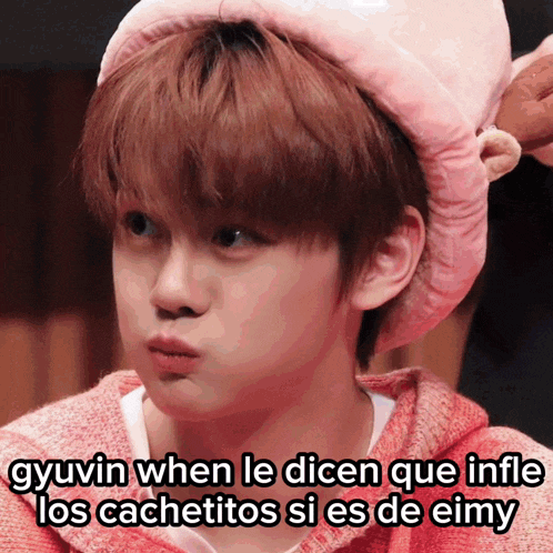 a young boy wearing a pink hat with the words gyuvin when le dicen que infle