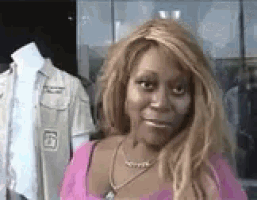 a woman is standing in front of a mannequin wearing a pink shirt and necklace .