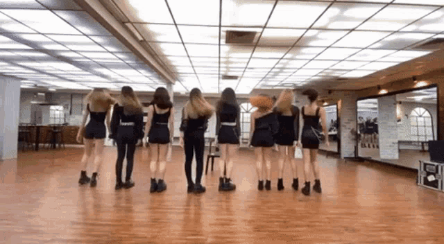 a group of women are standing in a room with their backs to the camera