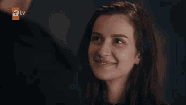 a woman is smiling in front of an a tv logo