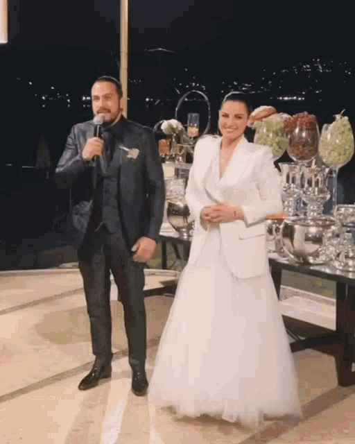 a man in a suit stands next to a woman in a wedding dress