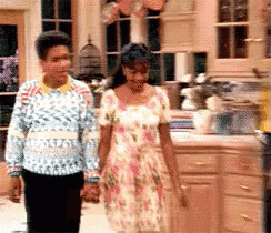 a woman in a floral dress walks with a man in a sweater