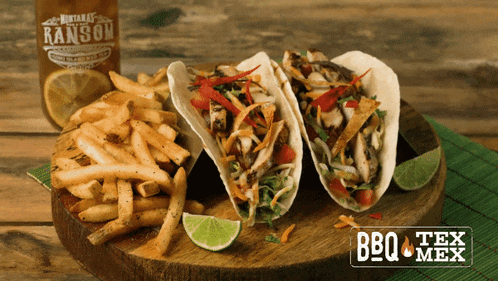 three tacos and french fries on a wooden cutting board with a bottle of ransom sauce in the background