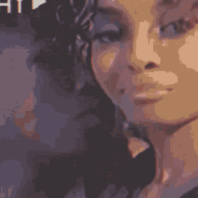 a close up of a woman 's face with the letter h visible in the background