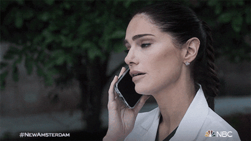 a woman in a lab coat is talking on a cell phone with the hashtag #newamsterdam