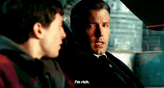 two men are sitting in a car and one of them is saying `` i 'm rich . ''