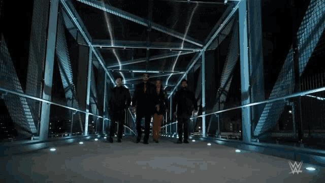 a group of people walking across a bridge with a w logo on the bottom right
