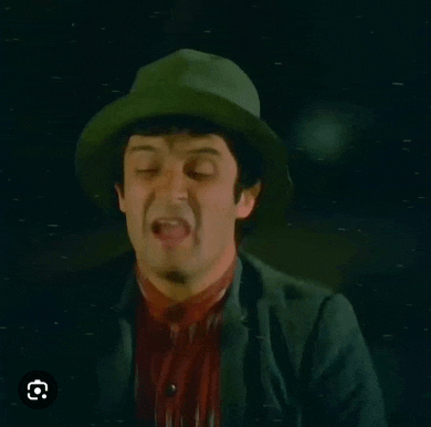 a man in a green hat is making a funny face .