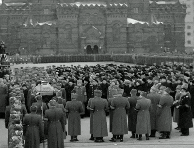 a black and white photo of a crowd of people standing in front of a building