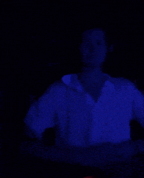 a man wearing headphones and a white shirt is standing in a dark room