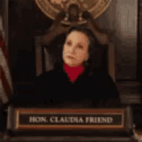 a woman is sitting in a judge 's chair with a name plate that says hon claudia freed