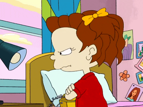 a cartoon girl with red hair and a yellow bow is sitting on a bed with a pillow