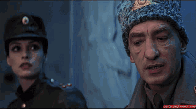a man and a woman are standing next to each other and the man is wearing a russian hat