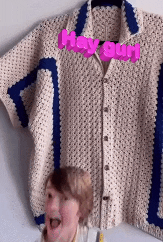 a man is standing in front of a crocheted shirt that says hey girl .