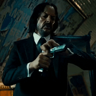 a man in a suit is holding a gun in his hand .
