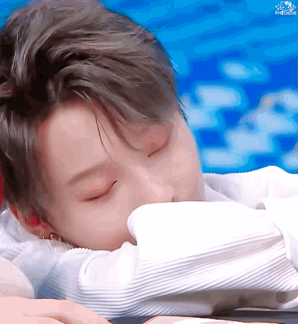 a close up of a person laying down with their eyes closed and a blue background