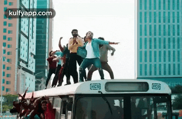 a group of people are dancing on top of a bus with hcu written on it