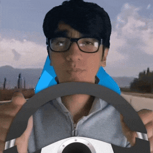 a man wearing glasses is holding a steering wheel in his hands