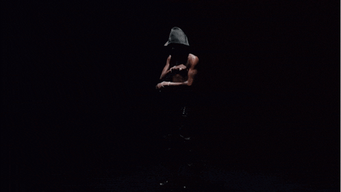 a shirtless man with a hood on his head is standing in the dark