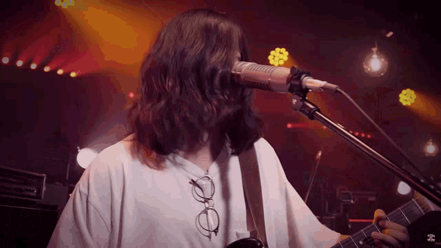 a man singing into a microphone while holding a guitar