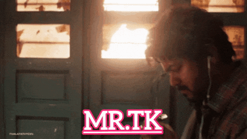 a man wearing ear buds is looking at his phone and the words mr.tk are on the screen