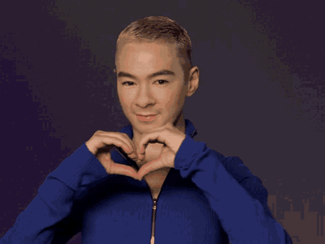 a woman in a blue jacket making a heart with her hands