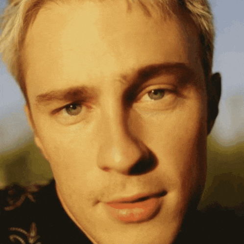 a close up of a man 's face with the letter r on his shirt
