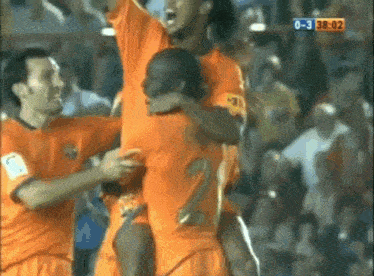 a group of soccer players are celebrating a goal in front of a crowd with a score of 0-3