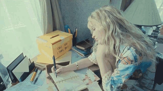 a woman sits at a desk writing in a notebook next to a box that says " two thousand small dots "
